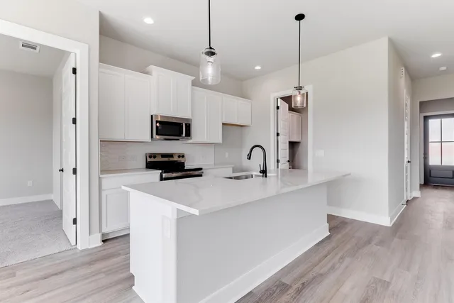 a kitchen with stainless steel appliances granite countertop a sink a stove a refrigerator and cabinets with wooden floor