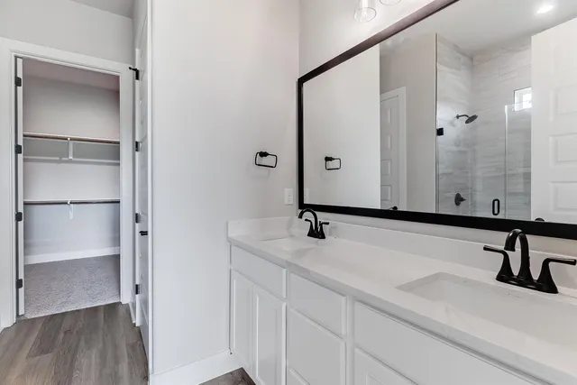 a bathroom with a double vanity sink a mirror and shower
