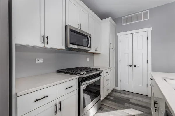 a kitchen with stainless steel appliances kitchen island granite countertop a stove a sink a dining table and chairs with wooden floor