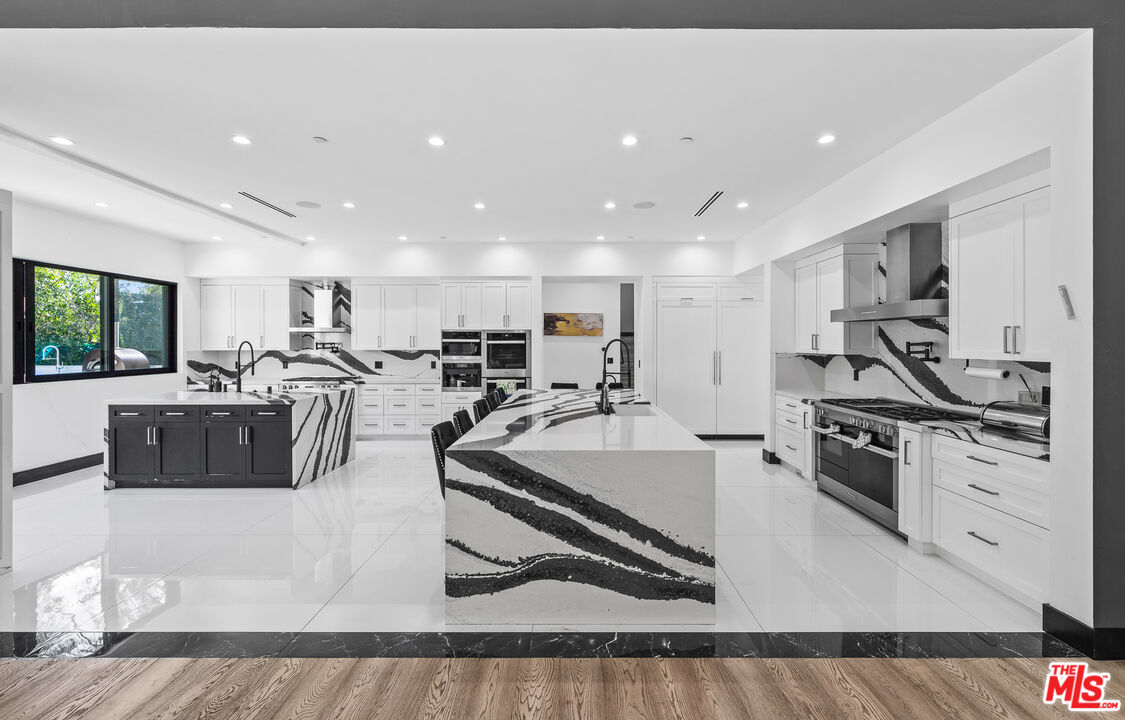 6006 Spring Valley Road Hidden Hills, CA 91302 - Photo 8 of 31 a large white kitchen with stainless steel appliances granite countertop a stove and a sink
