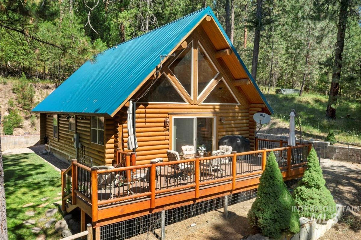 Back of house with a wooden deck, log siding, and a metal roof