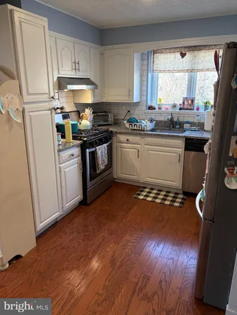 a kitchen with a sink wooden floor and black stainless steel appliances