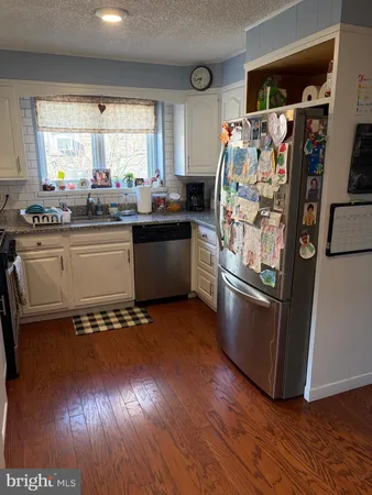 a kitchen with granite countertop a refrigerator and a stove top oven