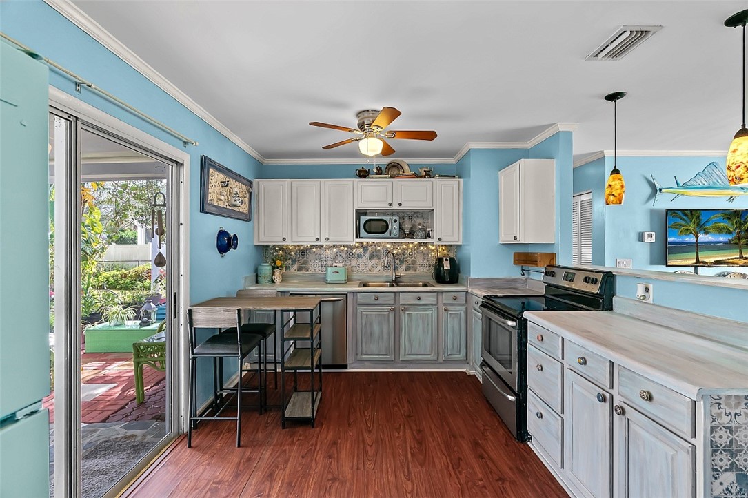 481 Warren Street Sebastian, FL 32958 - Photo 14 of 33 a kitchen with stainless steel appliances granite countertop a stove a refrigerator a sink dishwasher a dining table and chairs with wooden floor