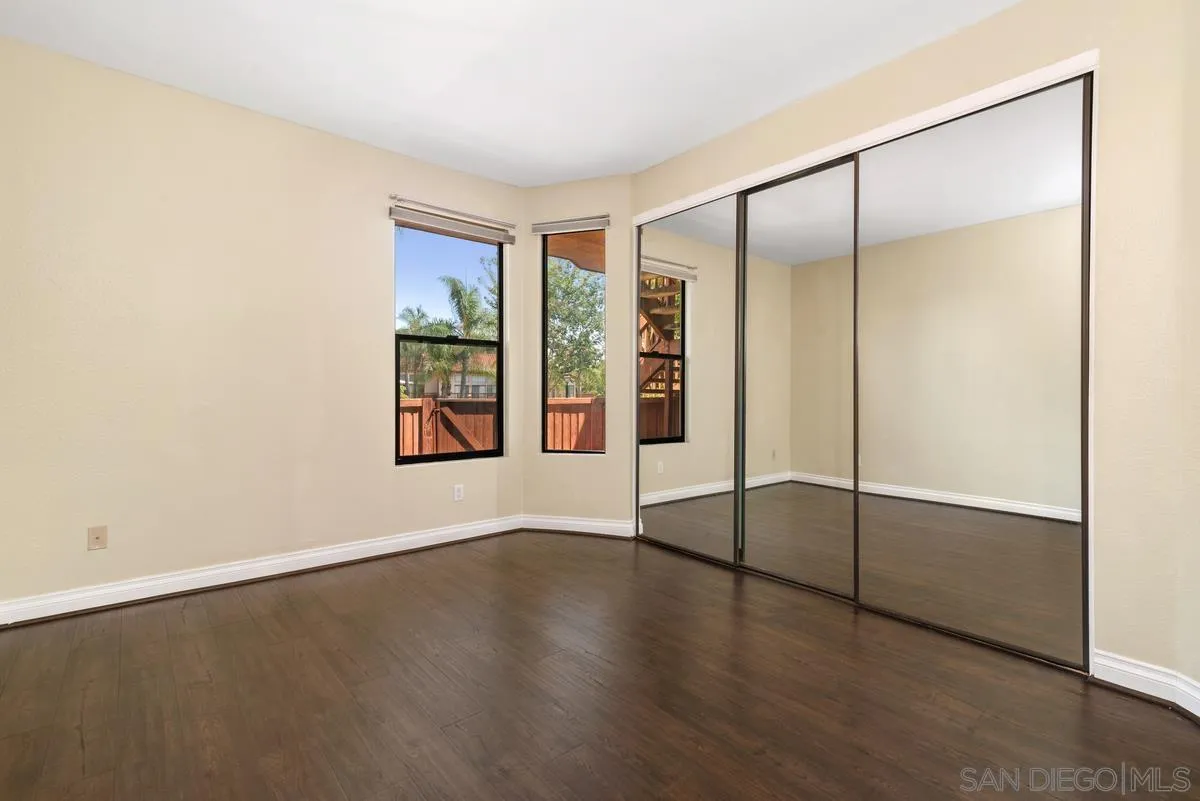 4049 Carmel View Road, Unit 75 San Diego, CA 92130 - Photo 9 of 13 an empty room with wooden floor and windows with curtains