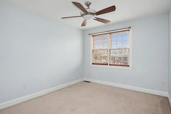 an empty room with a window and a fan