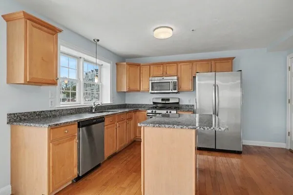 a kitchen with stainless steel appliances granite countertop a refrigerator a sink a stove and oven