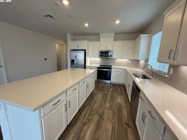 a kitchen with stainless steel appliances a sink dishwasher stove refrigerator and cabinets