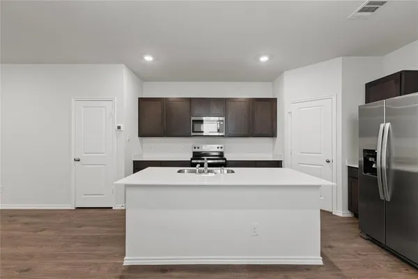 a large kitchen with stainless steel appliances a large counter top a stove and a refrigerator