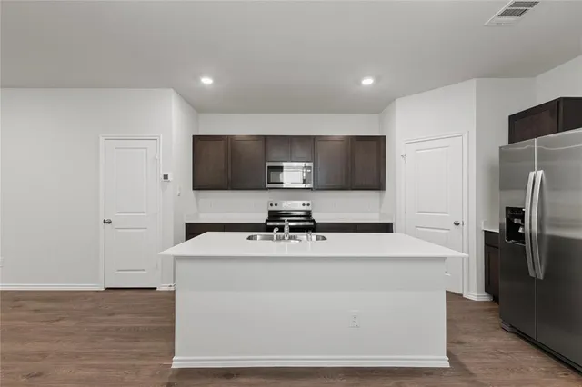 a large kitchen with stainless steel appliances a large counter top a stove and a refrigerator