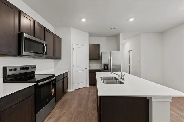 a kitchen with stainless steel appliances a sink microwave stove refrigerator and cabinets