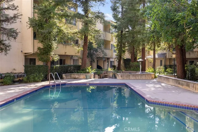 a swimming pool view with plants and large trees