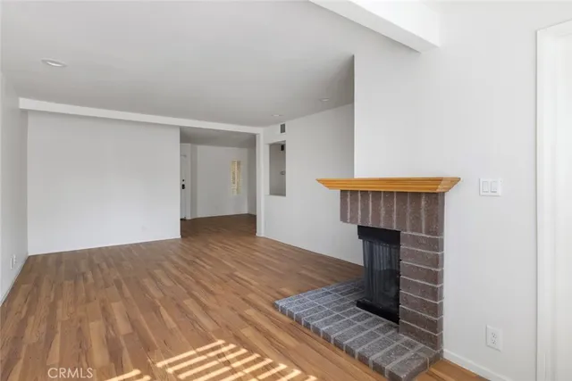 a view of empty room with wooden floor fireplace and rug