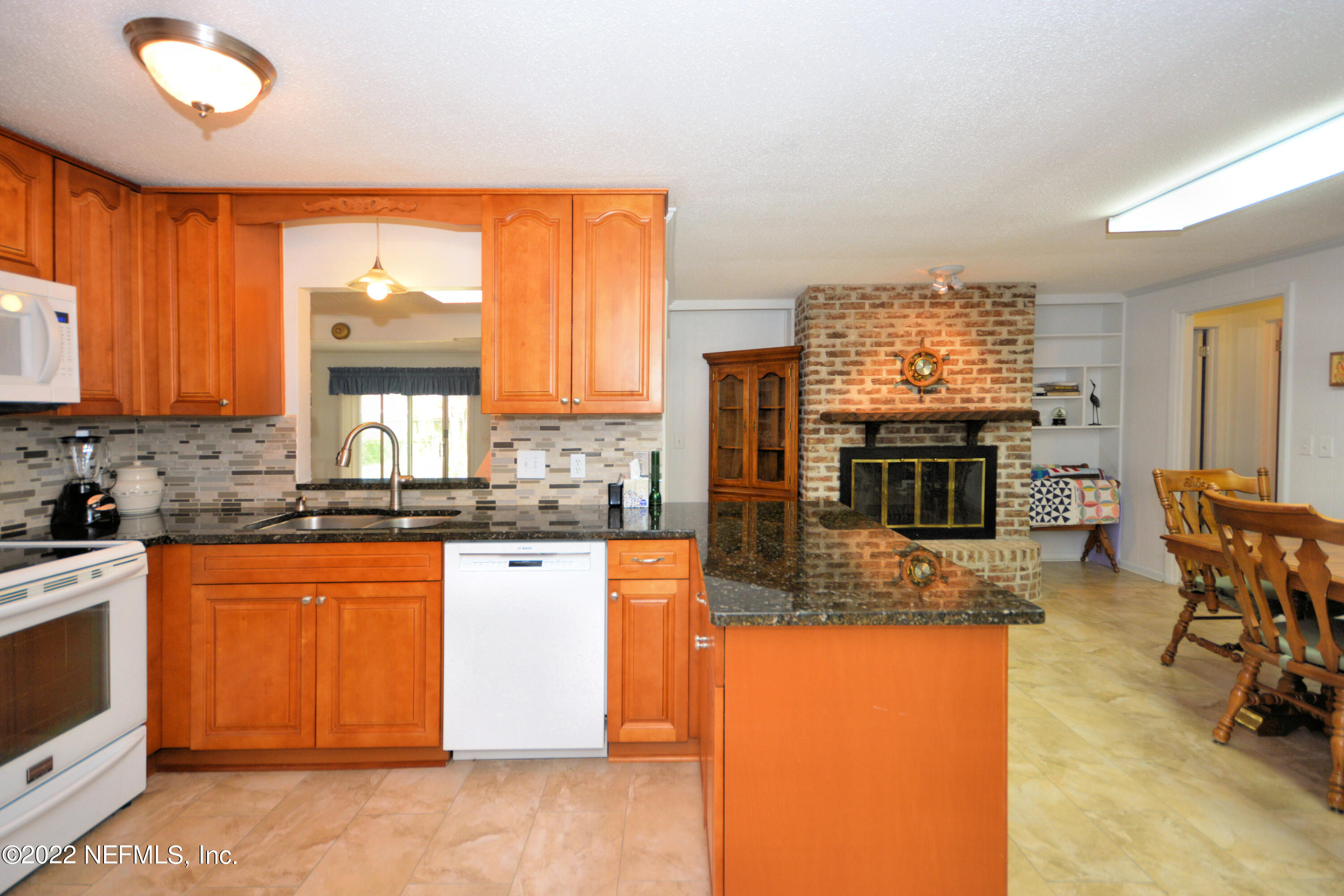 2282 Marcel Drive Orange Park, FL 32073 - Photo 12 of 29 a kitchen with stainless steel appliances granite countertop a stove top oven a sink dishwasher a dining table and chairs with wooden floor