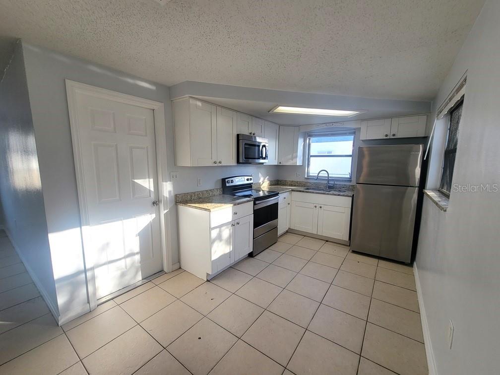 1415 Wickham Lane Holiday, FL 34691 - Photo 5 of 17 a kitchen with a refrigerator a stove top oven and cabinets