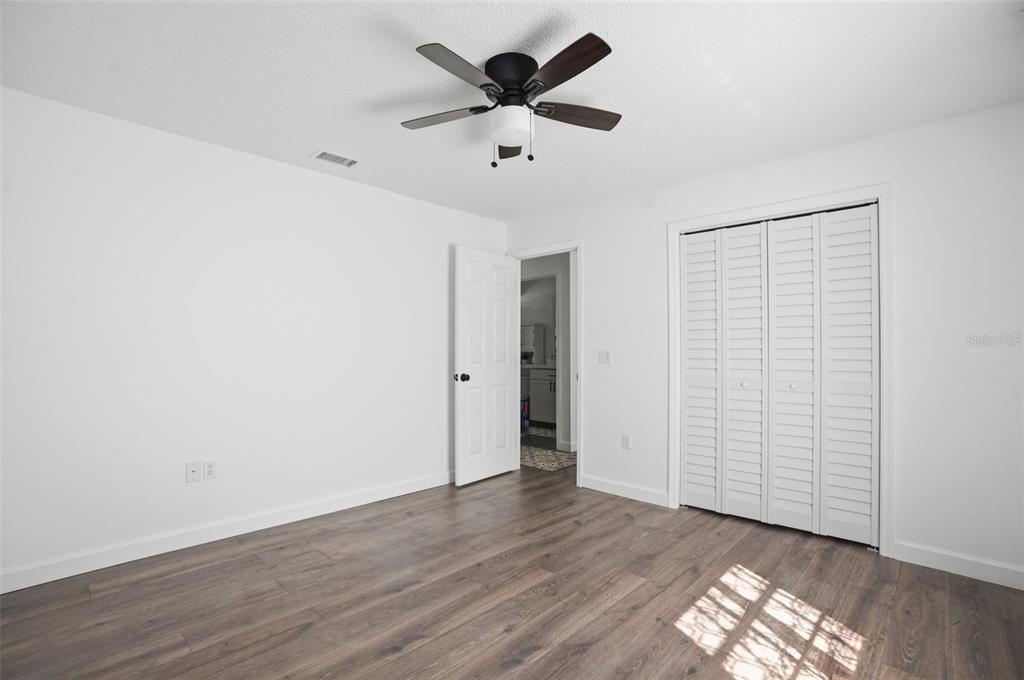 2076 Landover Boulevard Spring Hill, FL 34608 - Photo 22 of 37 an empty room with wooden floor and chandelier fan