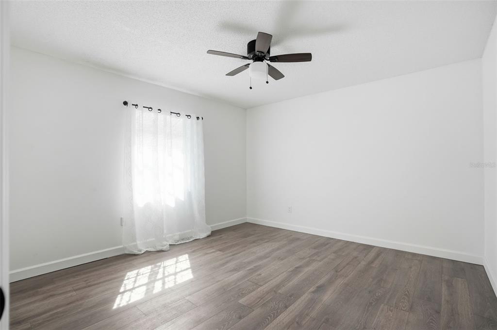 2076 Landover Boulevard Spring Hill, FL 34608 - Photo 24 of 37 an empty room with wooden floor fan and windows