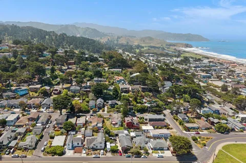 an aerial view of residential houses with outdoor space and ocean view