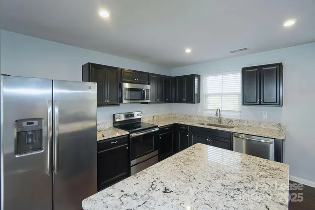 a kitchen with stainless steel appliances granite countertop a sink stove refrigerator and granite counter tops