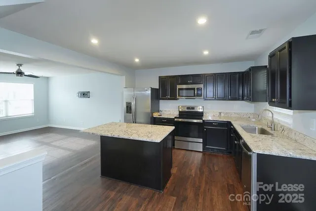a kitchen with granite countertop a sink stove and refrigerator