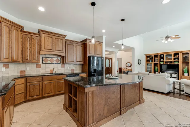 a kitchen with stainless steel appliances granite countertop a sink counter space cabinets and a view of living room