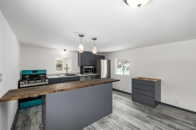 a kitchen with a refrigerator a stove a microwave oven and a dining table with wooden floor