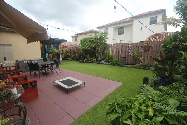 a view of a patio with table and chairs potted plants and floor to ceiling window and potted plants