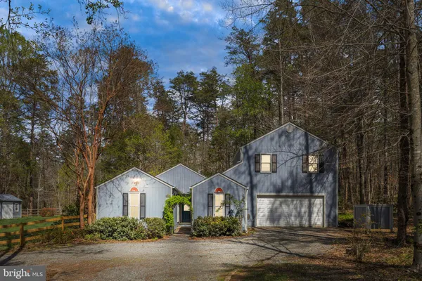 a front view of a house with a yard and large tree