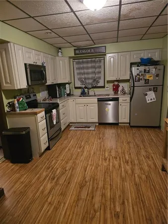 a kitchen with granite countertop a stove top oven a sink dishwasher and a refrigerator with wooden floor