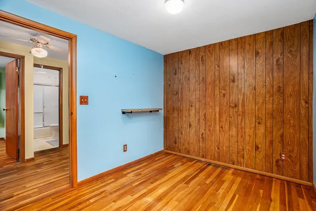 a view of empty room with wooden floor and fan