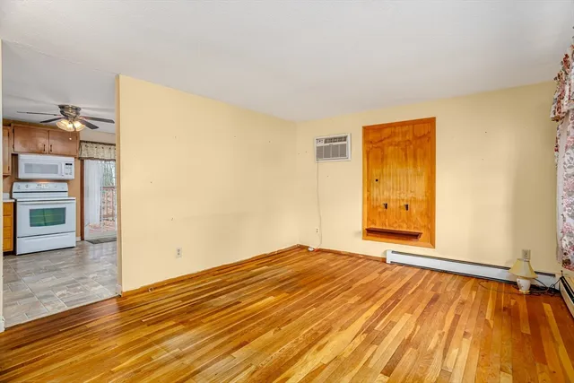 a view of an empty room with wooden floor and a window