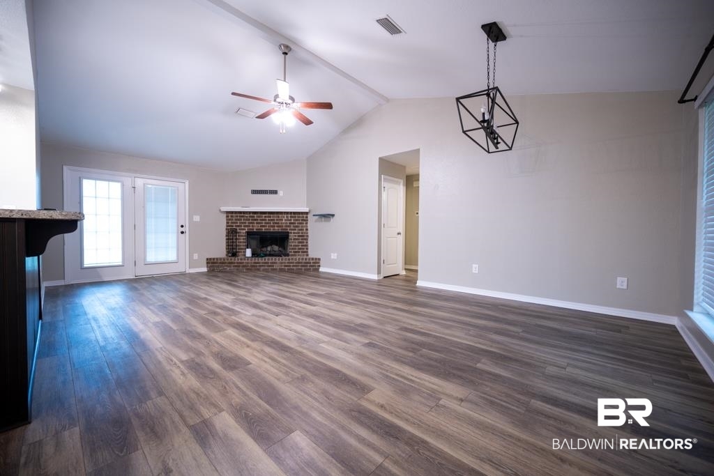 15874 Carver Road, Unit C Foley, AL 36535 - Photo 8 of 18 Unfurnished living room with vaulted ceiling, dark hardwood / wood-style flooring, a brick fireplace, and ceiling fan