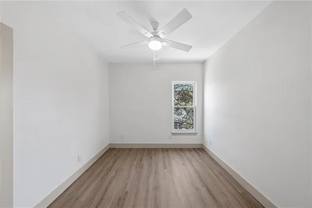 an empty room with a window and a fan
