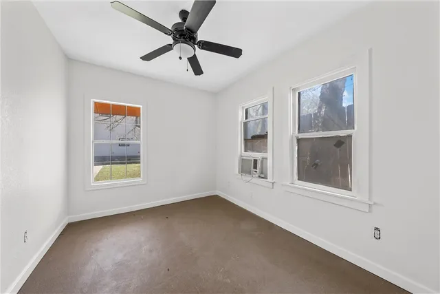 an empty room with a window and a ceiling fan