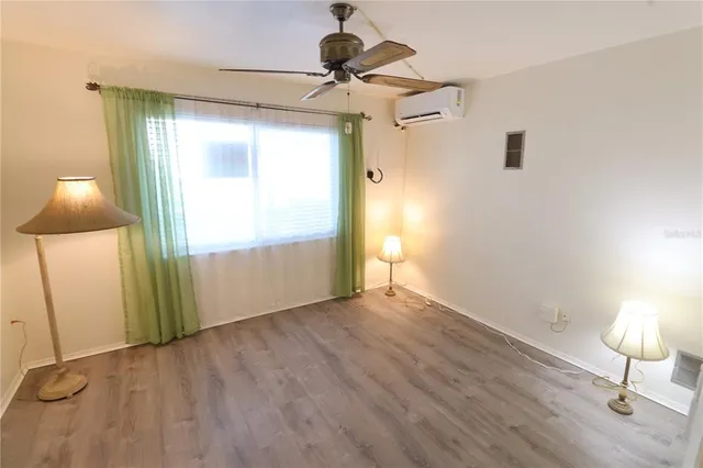 a view of an empty room with a window and wooden floor