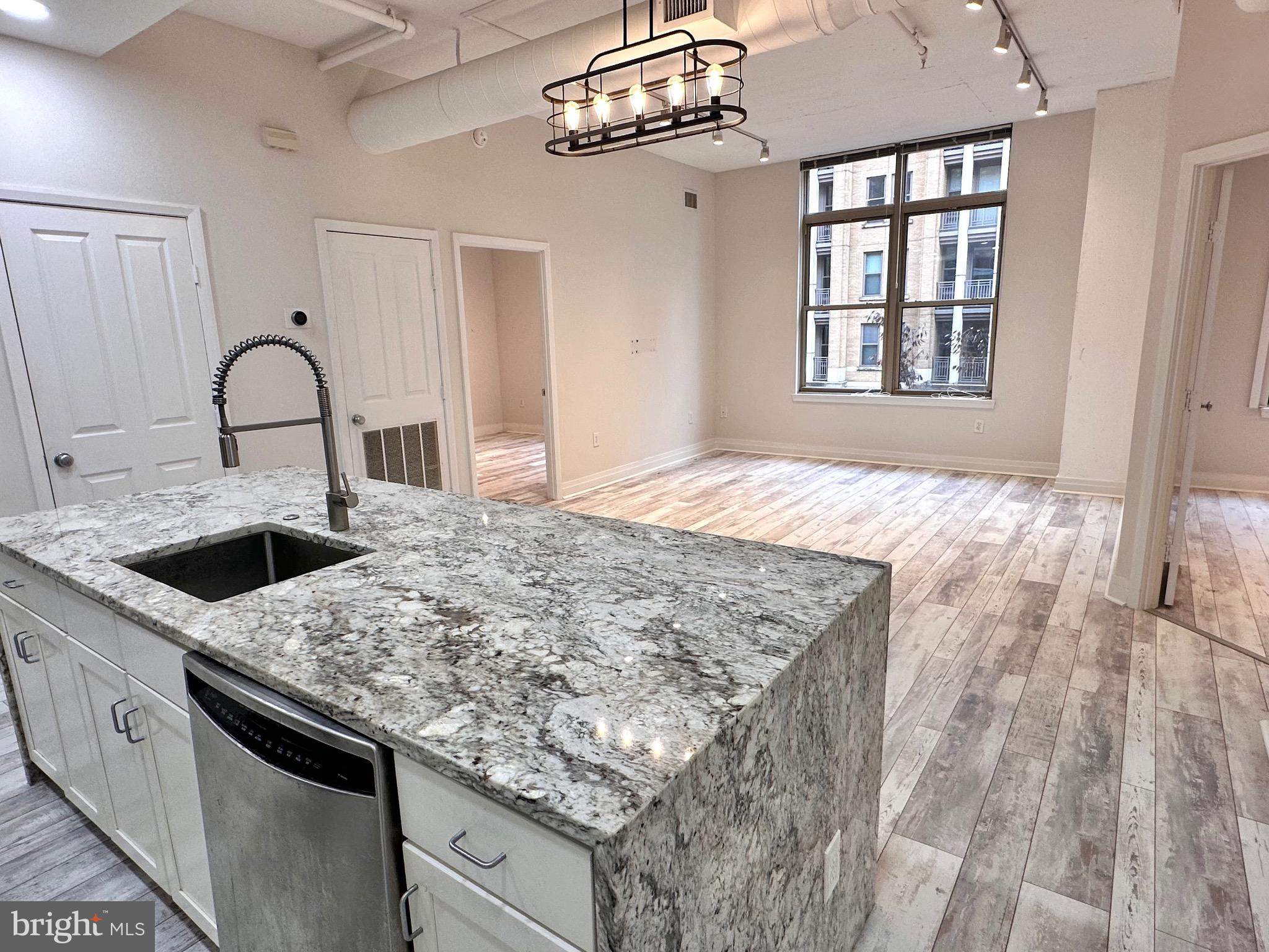 1201 North Garfield Street, Unit 408 Arlington, VA 22201 - Photo 25 of 26 a kitchen with stainless steel appliances granite countertop a sink dishwasher and white countertops with wooden floor