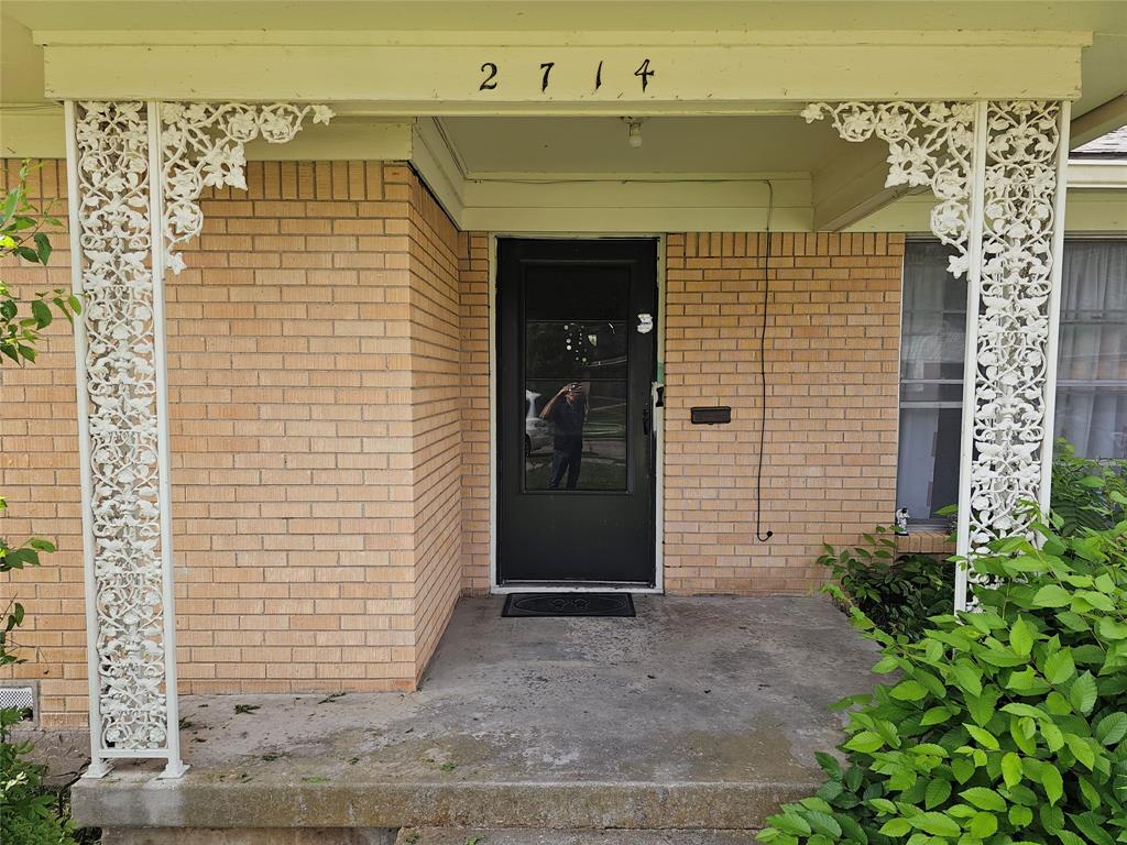 2714 Crest Ridge Drive Dallas, TX 75228 - Photo 2 of 15 Covered front entry featuring ornate white ironwork columns, a dark entry door with glass paneling, and a light brick facade
