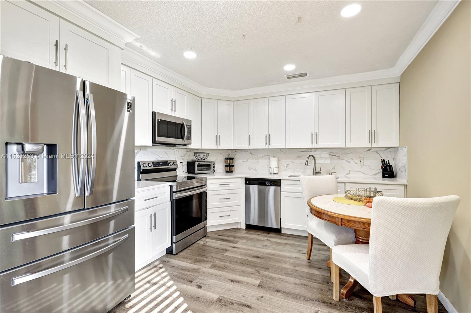 a kitchen with cabinets stainless steel appliances and wooden floor