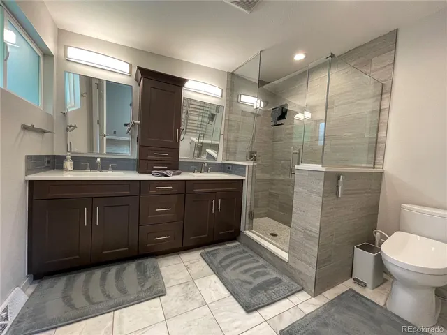 a bathroom with a double vanity sink toilet and shower