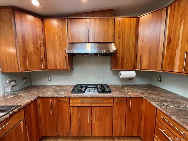 a kitchen with granite countertop wooden cabinets a sink and a stove top oven