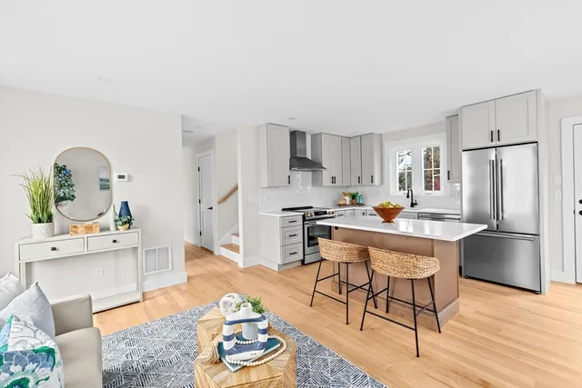 a kitchen with stainless steel appliances granite countertop a refrigerator a stove a sink dishwasher and white cabinets with wooden floor