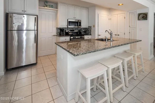 a kitchen with granite countertop a table chairs microwave and refrigerator