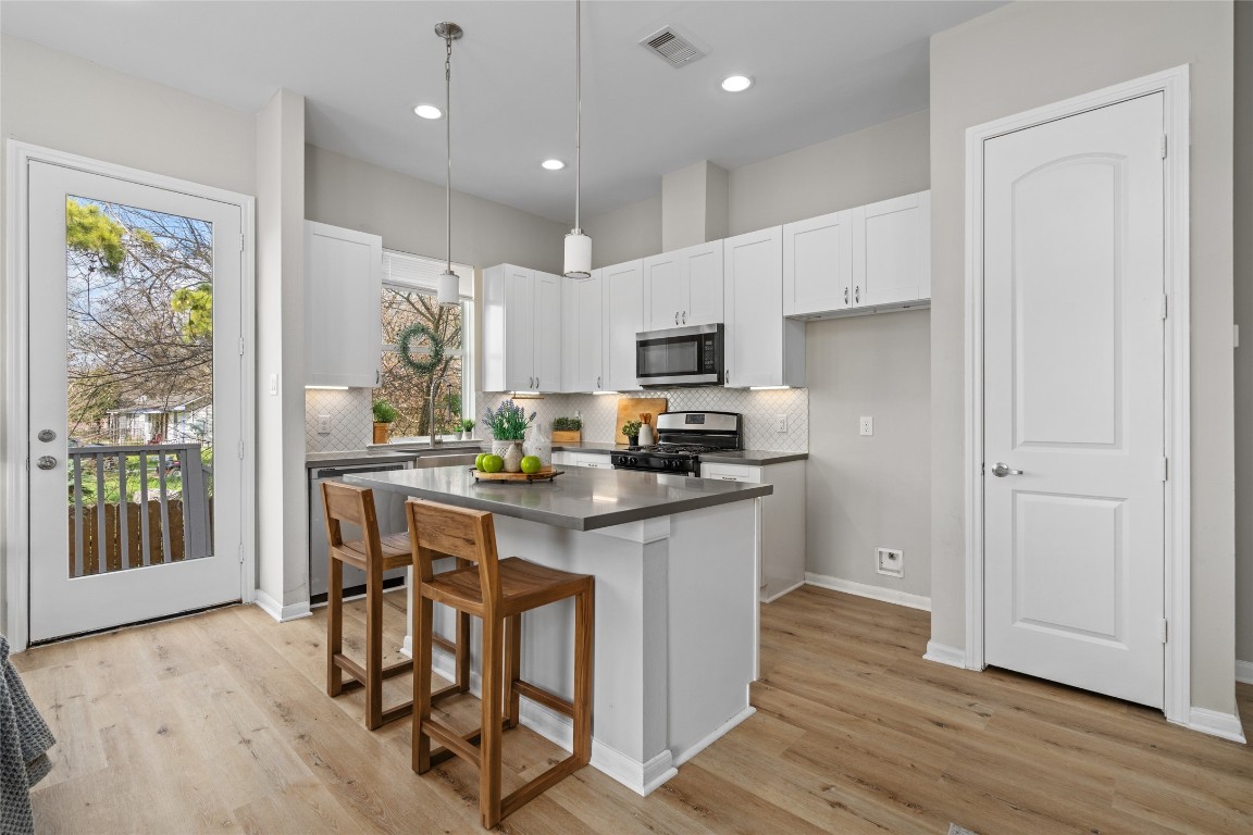 5610 Patrick Street, Unit L Houston, TX 77076 - Photo 12 of 28 a kitchen with kitchen island granite countertop wooden floors and white cabinets