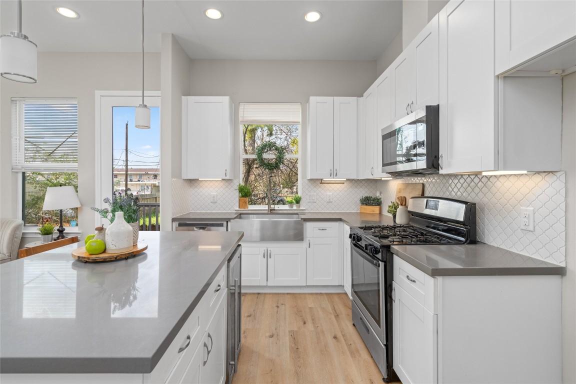 5610 Patrick Street, Unit L Houston, TX 77076 - Photo 4 of 28 a kitchen with a sink a stove a refrigerator and white cabinets with wooden floor