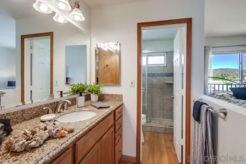 a bathroom with a granite countertop sink a mirror and a shower