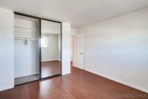 a view of an empty room with wooden floor & closet