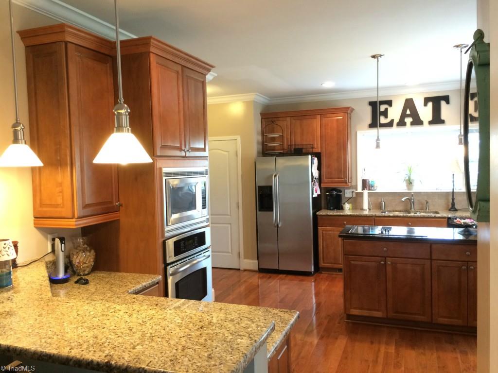 794 Sheep Farm Road Mount Airy, NC 27030 - Photo 7 of 30 Custom cabinetry, island with cooktop, granite counters and stainless steel appliances