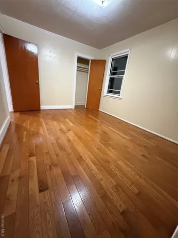 a view of an empty room with wooden floor and stairs