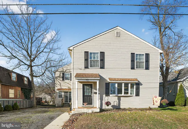 a view of a white house with a large tree