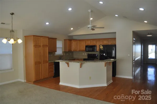 a kitchen with stainless steel appliances granite countertop a refrigerator a sink a stove and a refrigerator